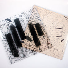Load image into Gallery viewer, Two square Mayday Parade sheets overlap on a white surface, both covered in mixed black text fragments. One features bold black lines; the other is beige with faded, scattered letters.