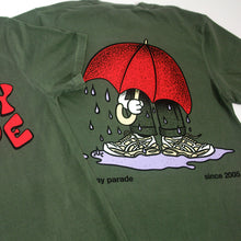 Load image into Gallery viewer, image of the back of a moss green tee shirt. tee has a full body print of a person with a big red umbrella standing in a rain puddle
