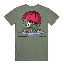 Load image into Gallery viewer, image of the back of a moss green tee shirt. tee  has a full body print of a person with a big red umbrella standing in a rain puddle
