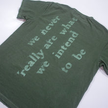 Load image into Gallery viewer, A green Mayday Parade Comfort Colors T-Shirt laid flat, featuring the text “we never really are what we intend to be” in large, faded puff print letters on the back.
