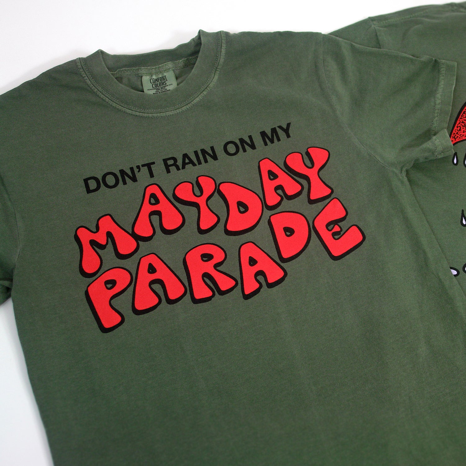 image of the front of a moss green tee shirt. tee has a center chest print that says don't rain on my mayday parade