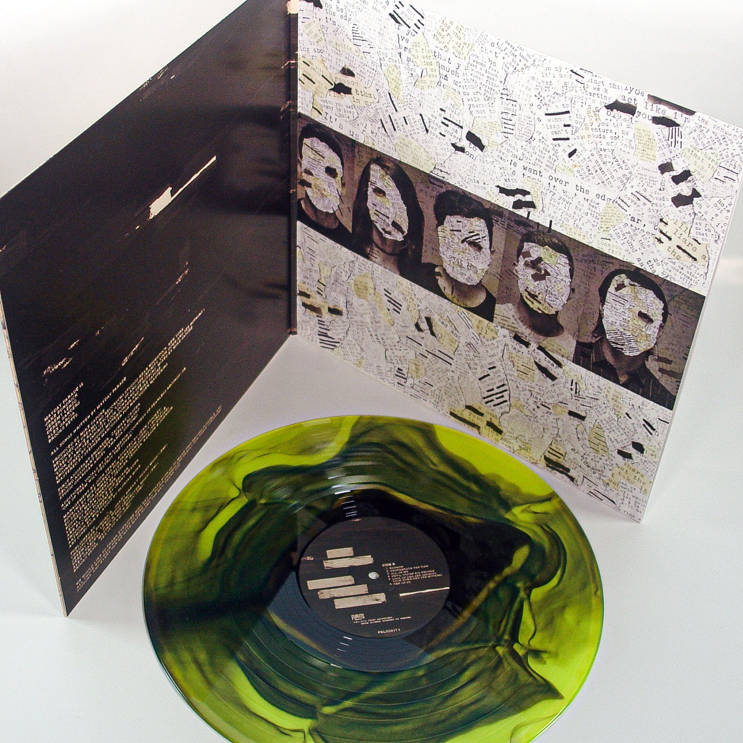 A green and black marbled vinyl LP by Mayday Parade sits before an open album cover showcasing abstract art, song lyrics, and black-and-white faces partially hidden by collage details.