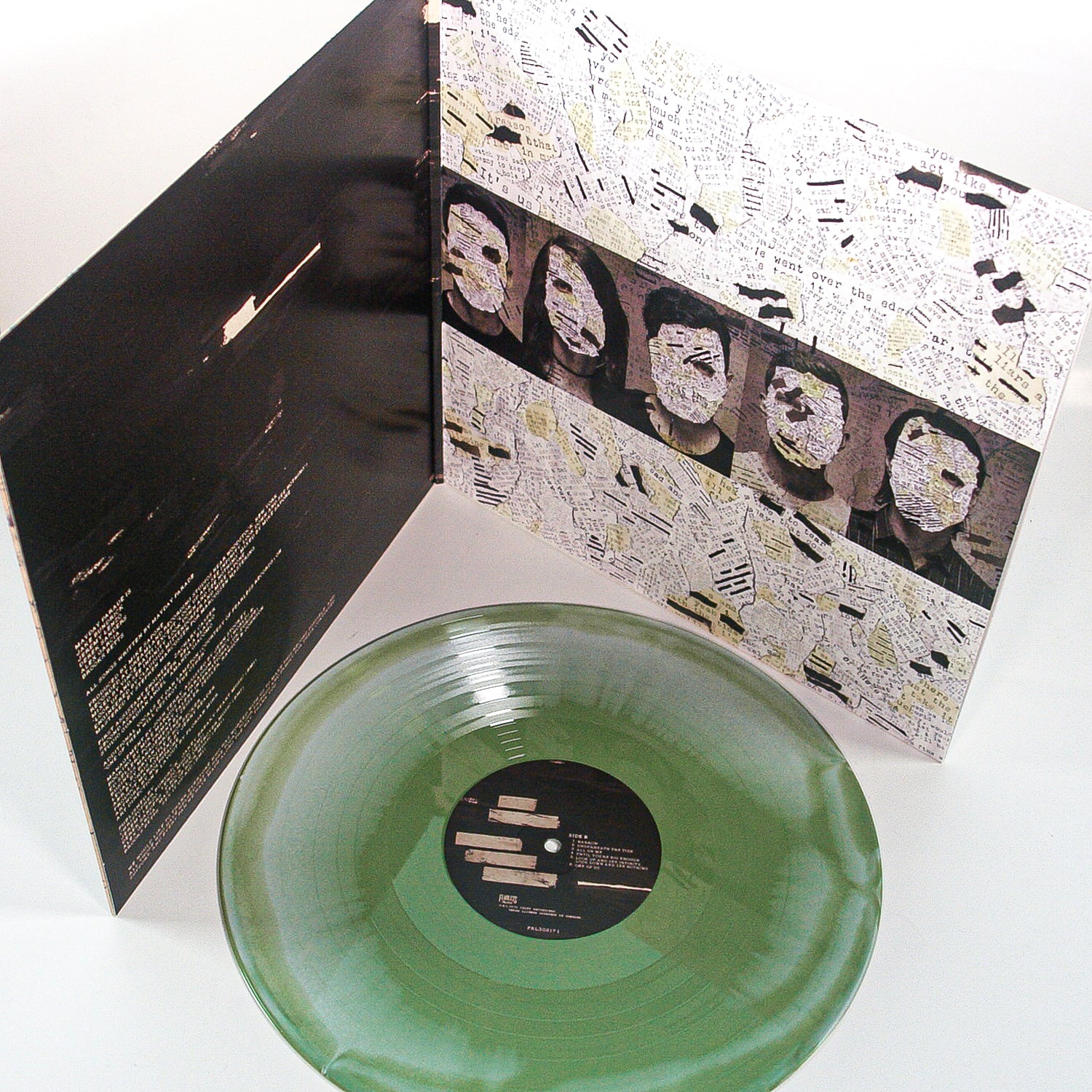 A translucent olive green Vinyl LP from Mayday Parade sits in front of an open album cover with black-and-white collage art, obscured faces, and handwritten text. The inner sleeve features song lyrics, album credits, and bold black lines.
