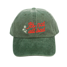 Load image into Gallery viewer, A green Mayday Parade LP101 Adams Pigment Dyed Dad Hat with white stitching, featuring &quot;It&#39;s not all bad&quot; embroidered in red and two white flower outlines on the front.

