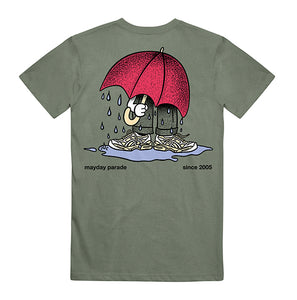 image of the back of a moss green tee shirt. tee  has a full body print of a person with a big red umbrella standing in a rain puddle