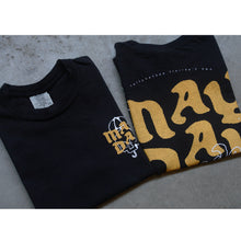 Load image into Gallery viewer, image of front and back of a black tee shirt folded and laid on a concrete floor. the front of the tee is on the left and has a grey size tag on the inside neck and a small chest print on the right in yellow and white print. the back of the tee is on the right and shows a full size print in yellow that says may day
