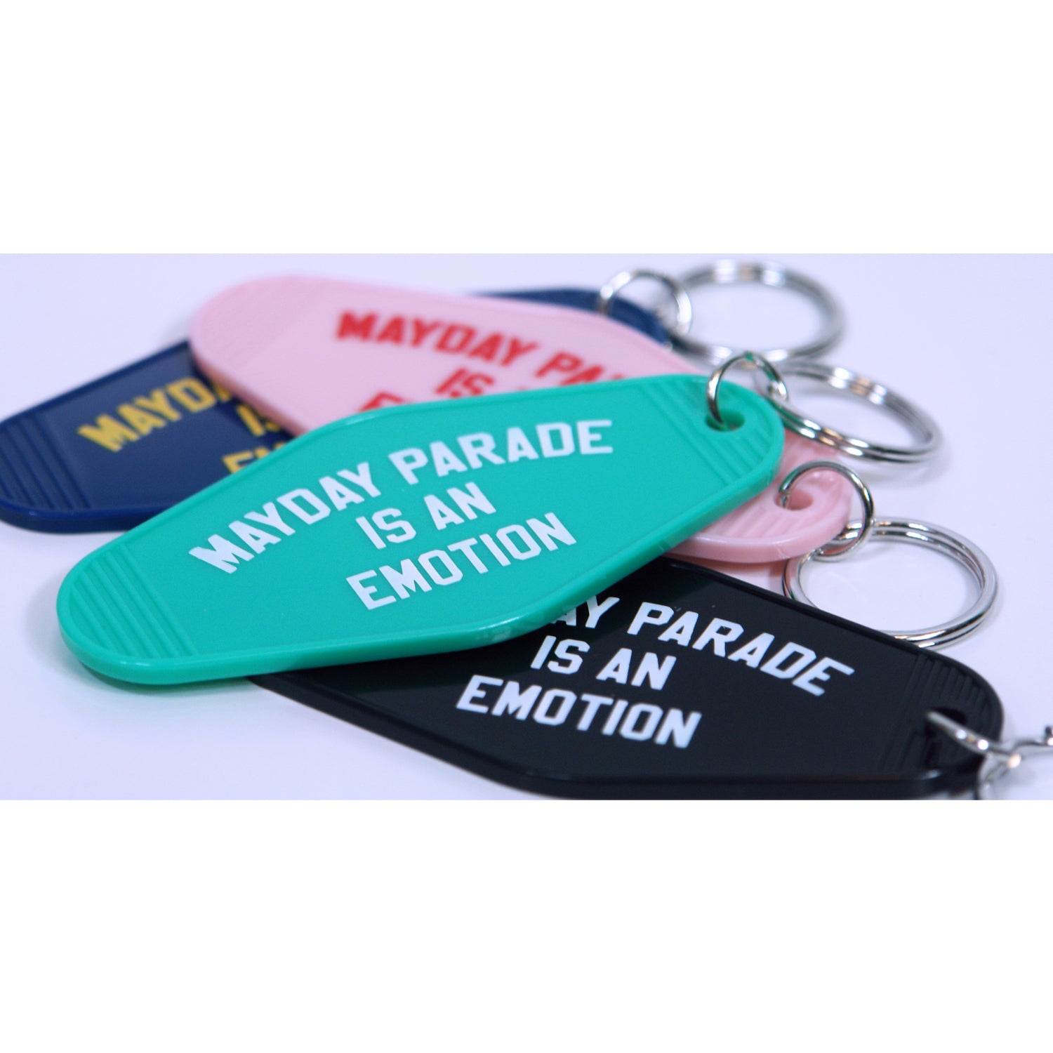image of a stack of keyrings in various colors on a white background. the key rings say mayday parade is an emotion
