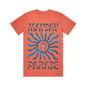 image of the front of a salmon colored tee shirt on a white background. tee has a full body print. at the top says mayday and the bottom says parade. in the center is a blue sun shape and inside says is an emotion.